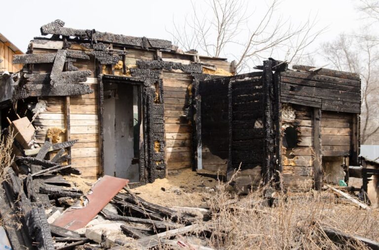 Brown and black burnt house of wooden planks with embossed texture without door and broken wall.